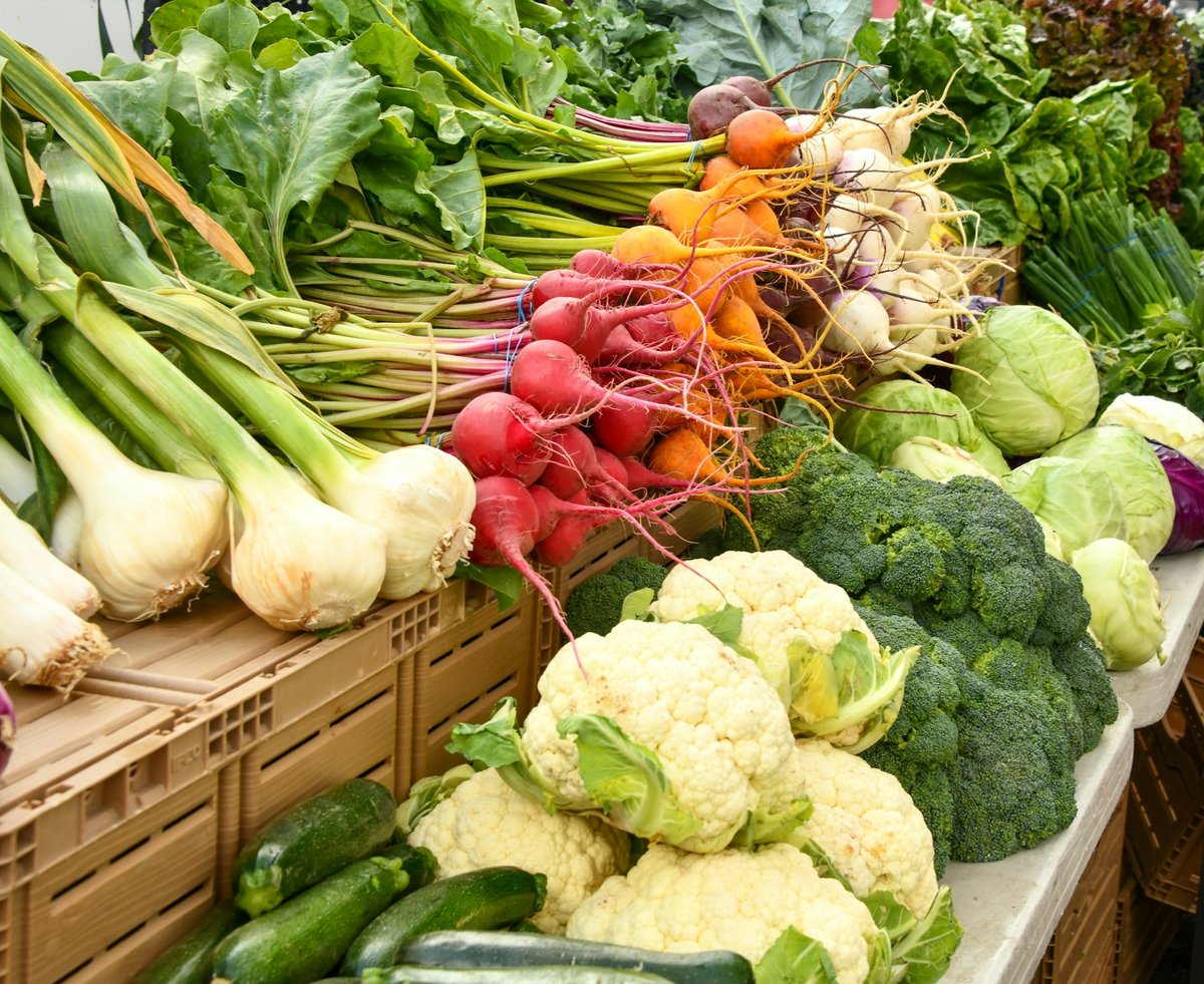 Étal de marché avec poireaux, radis, choux-fleurs et brocolis