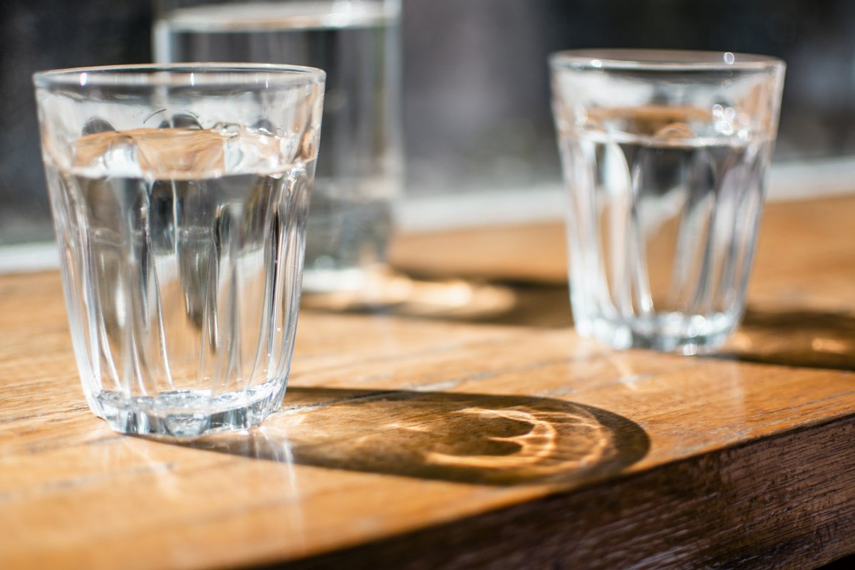 Verres d'eau sur une table en bois au soleil